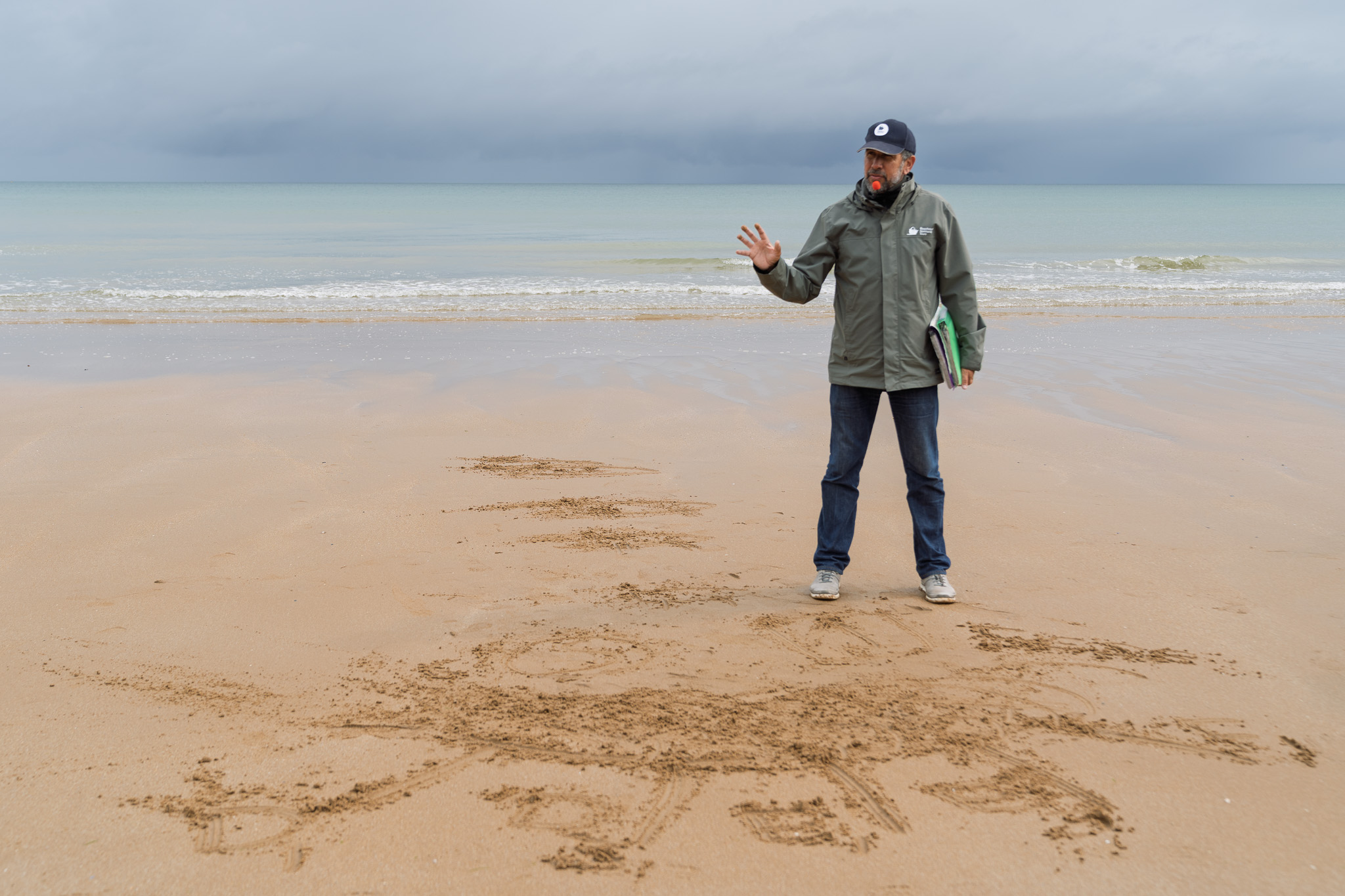 D-Day Guide Mathias Leclerc drawing the D-Day landings in the sand on Utah Beach on the anniversary of D-Day
