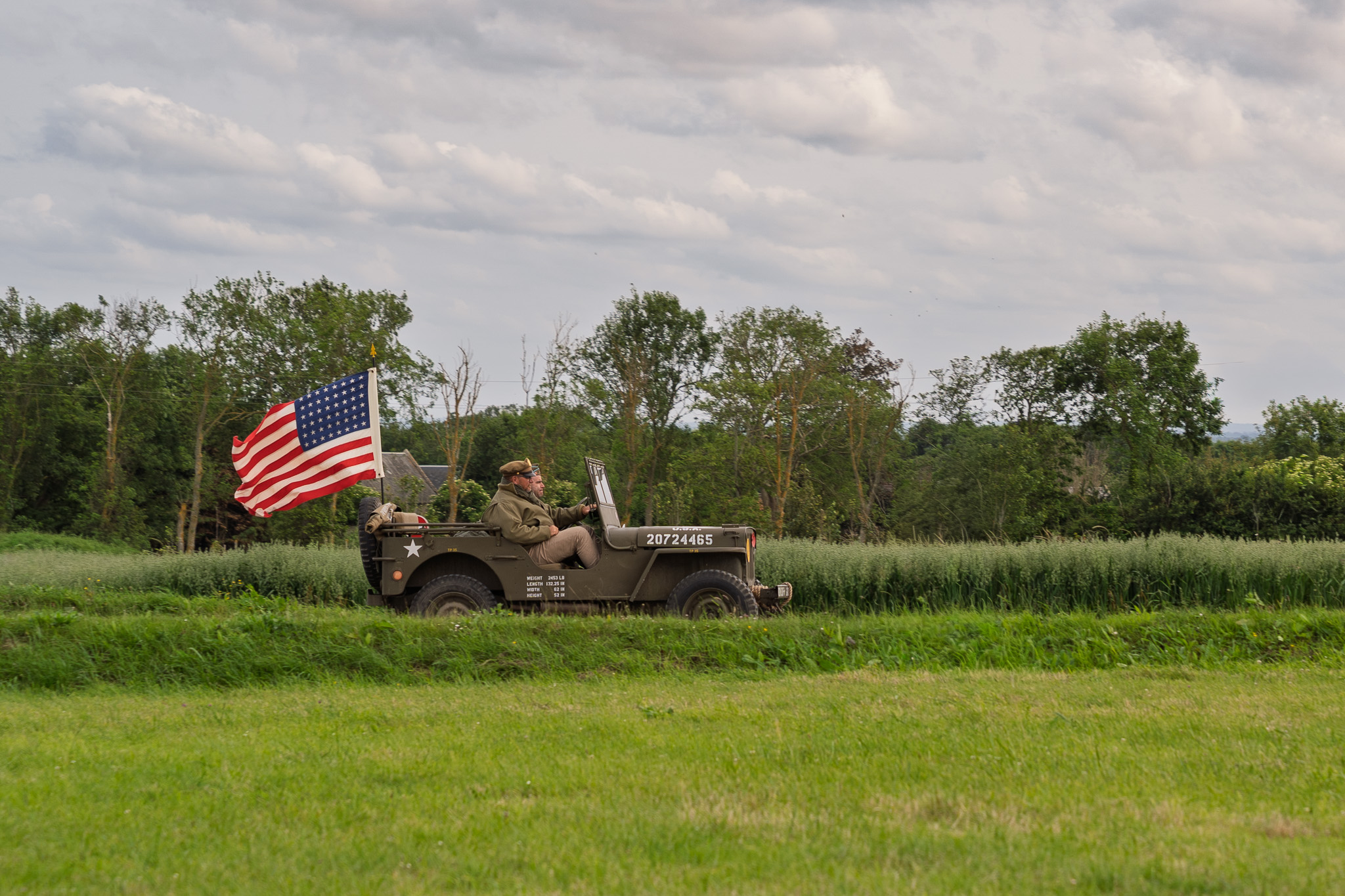 Vintage WWII Jeep traveling on a country road in Normandy, France the anniversary of D-Day.