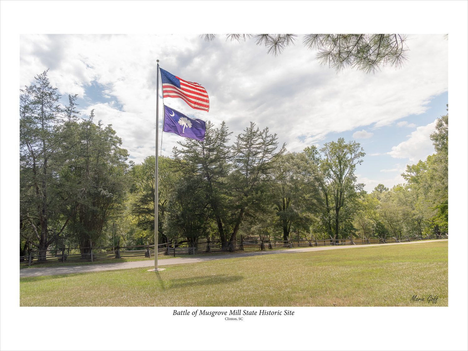 US and SC flags fly at the Battle of Musgrove Mill with the split rail fence in the background.