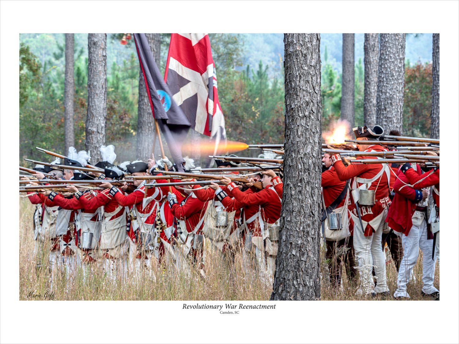 Royals form up and fire during a Revolutionary War reenactment. Fire is exploding out of the guns.