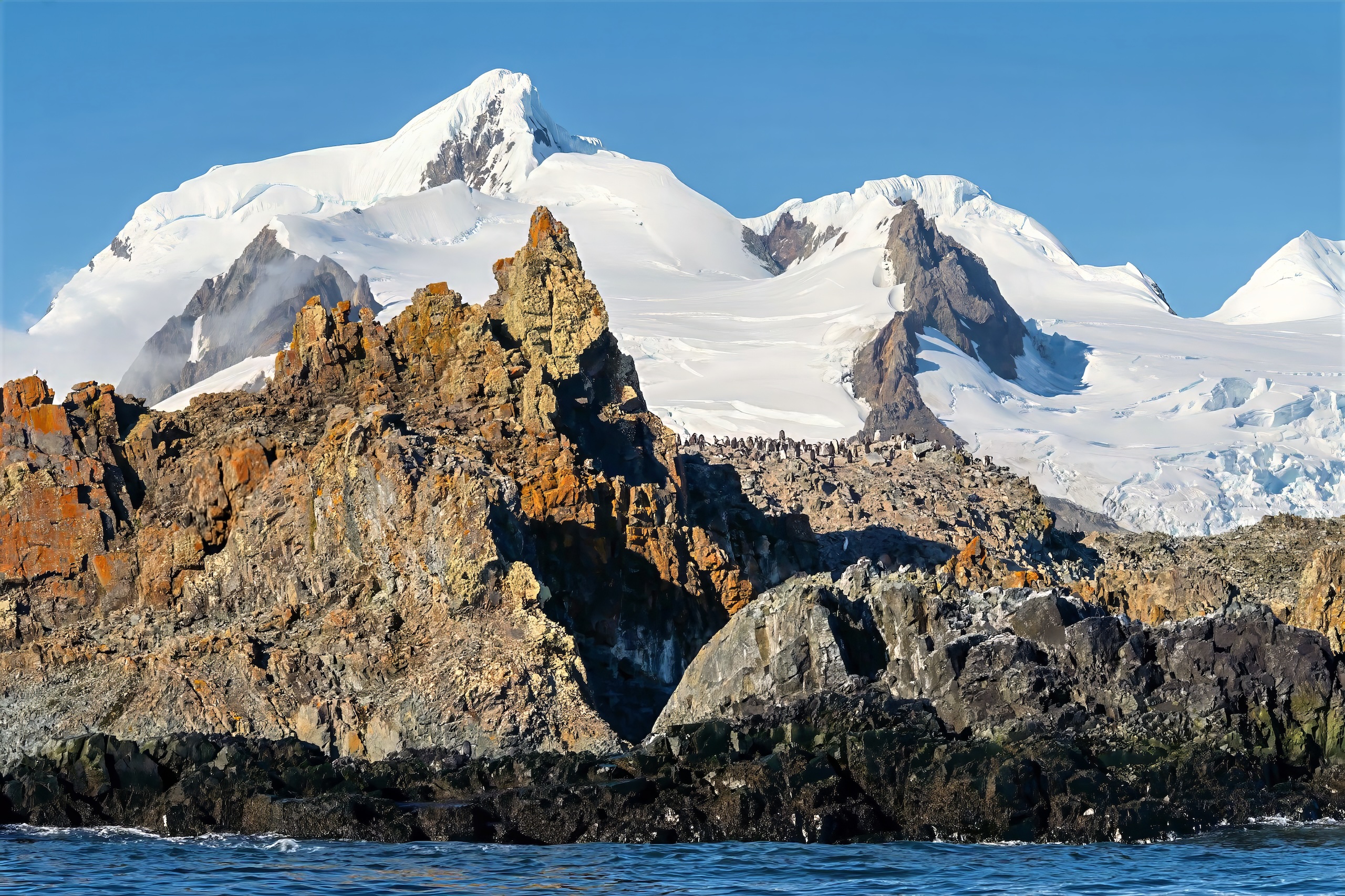 Snowcapped mountain scene wth penguins in Antarctica.