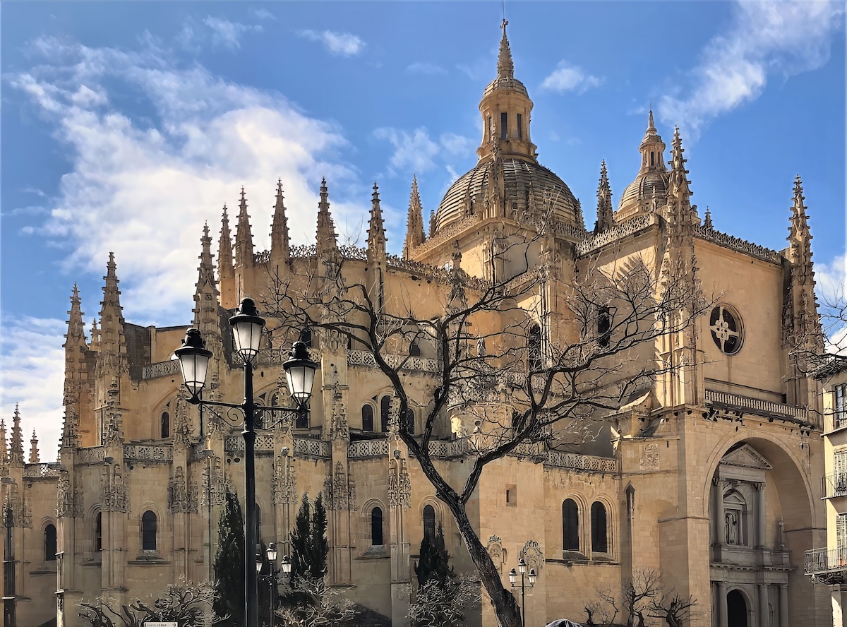 A traveler exploring Segovia views the dramatic gothic spires of Segovia Cathedral from teh plaza.