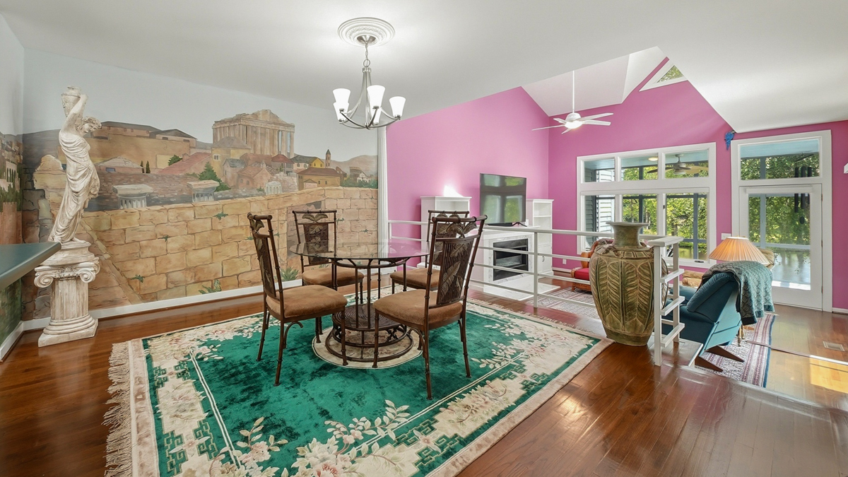 Gateway to the world in the dining room with table and chairs and a wall mural with the parthenon painted on it. Beyond that is the pink living room.