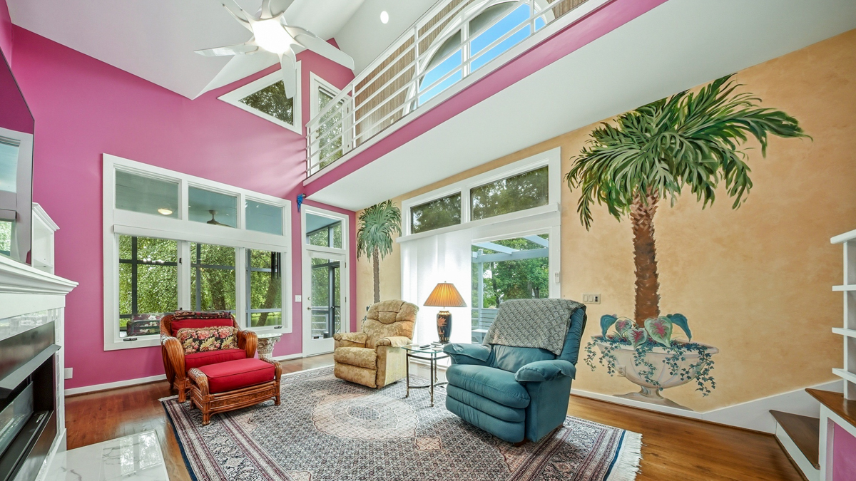 Living room with pick walls and murals of palmetto trees in a pot on the walls.