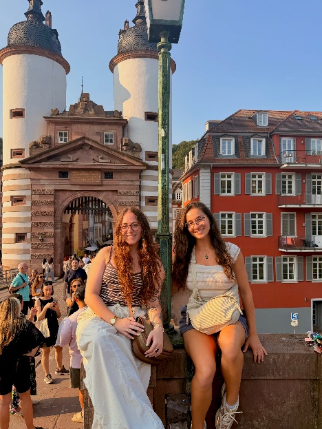 Meredith and Tina at Bridge Gate, Old Bridge, Heidelberg. The Bridge Gate ia a historic medevil gateway with twin white-washed towers. You can see that they are happy creating this story of a backpack full of memories.