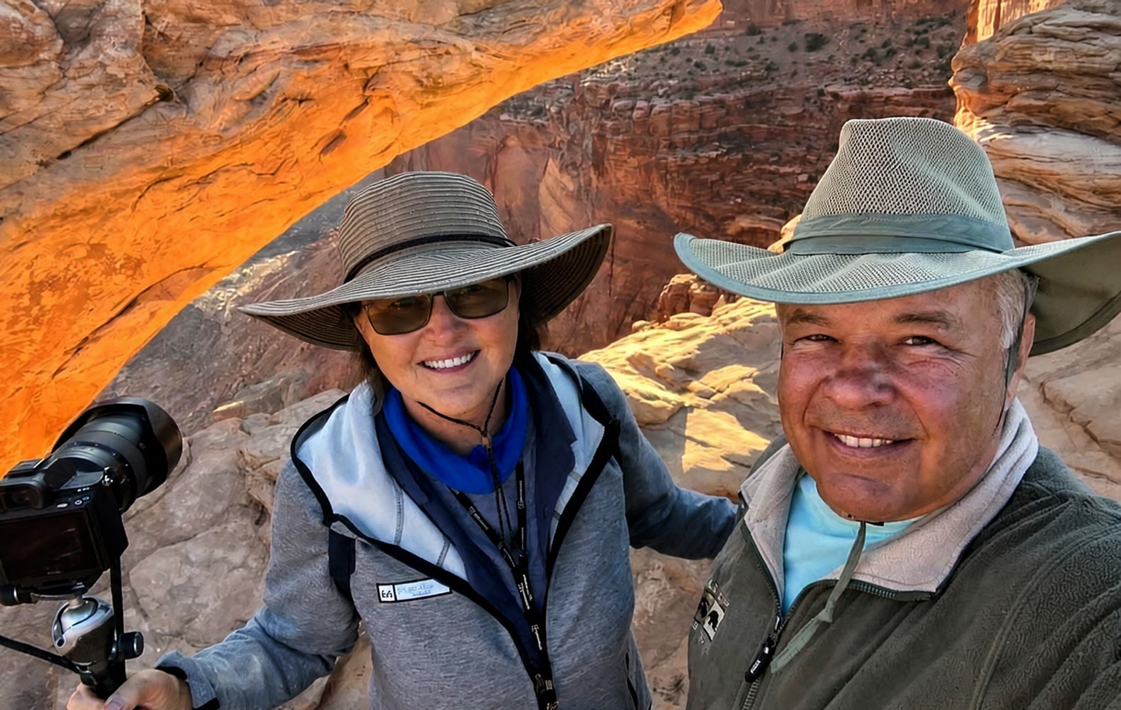 Marie and Eddie at Mesa Arch Marie and Eddie in front of Mesa Arch at gold hour taking a selfie.